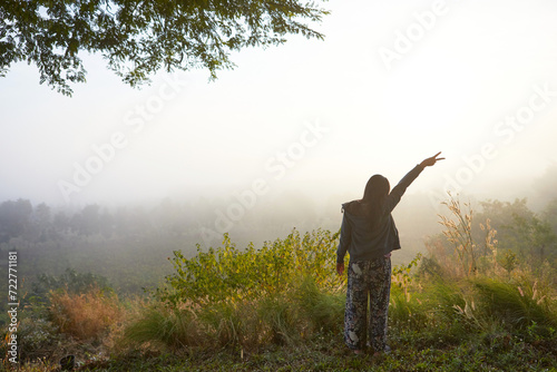Rear view of woman standing in forest during misty morning
