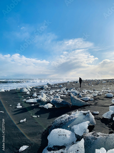 Woman wanders through iceberg chunks on Diamond Beach in Iceland photo