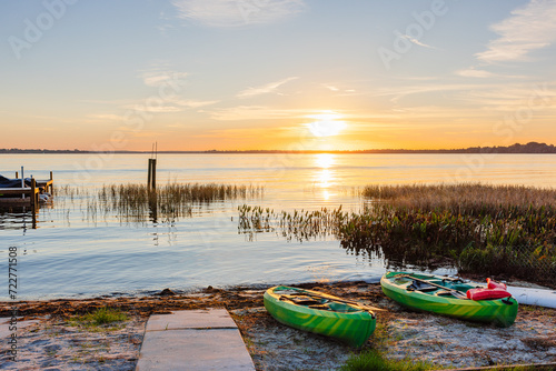 Fototapeta Naklejka Na Ścianę i Meble -  Serene lake sunrise with kayaks on beach ready for adventure