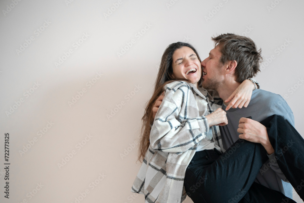 A playful young couple shares an intimate hug while balanced on a chair, their expressions reflecting happiness and affectionate enjoyment. A playful young couple shares an intimate hug while balanced on a chair, their expressions reflecting happiness and affectionate enjoyment.