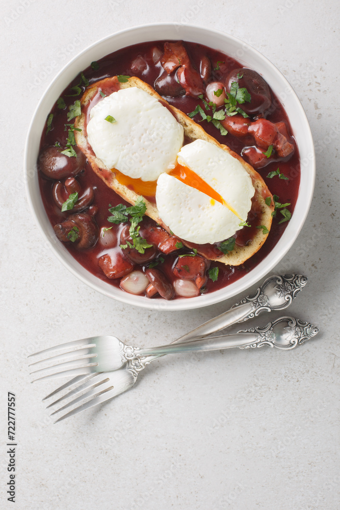 Eggs meurette or poached eggs with red wine sauce closeup on the plate on the table. Vertical top view from above