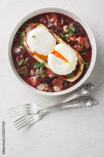 Eggs meurette or poached eggs with red wine sauce closeup on the plate on the table. Vertical top view from above