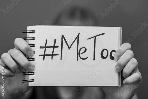 #MeToo napis na kartce trzymany przez kobietę w dłoni, czarno-biale zdjęcie 