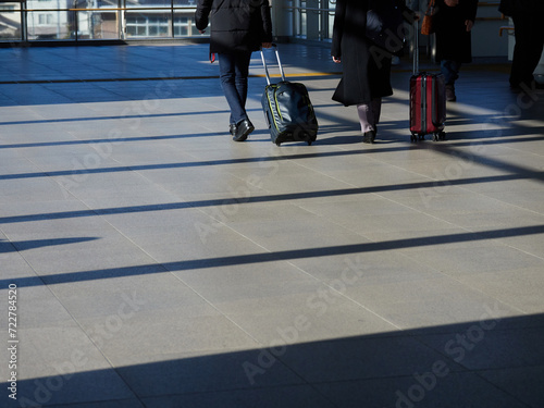 駅で歩くスーツケースを持っている男女ビジネスマンの姿