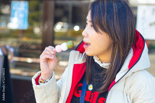 Fotografie Beautiful woman eating sanshoku dango or hanami dango in the street at Hikone, S