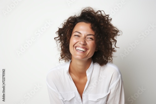 Portrait of a happy young woman with curly hair laughing against white background