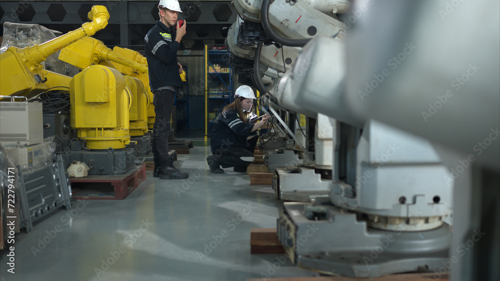 Both of engineers working together in a robotic arm factory, Robotic arm industry and engineering concept. Both of engineers working together in a robotic arm factory, Robotic arm industry and engineering concept.
