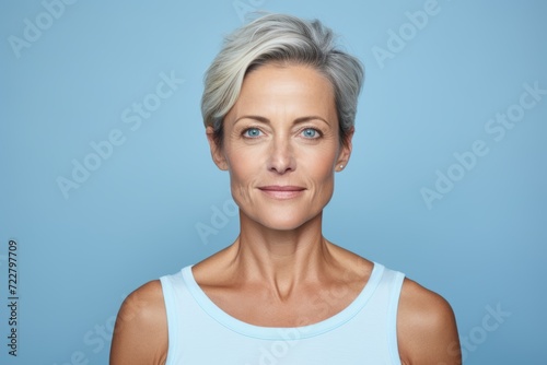 Portrait of beautiful middle aged woman looking at camera while standing against blue background
