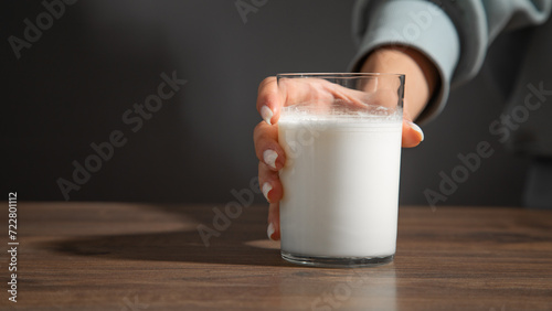Hand holding a glass of milk on the table. photo