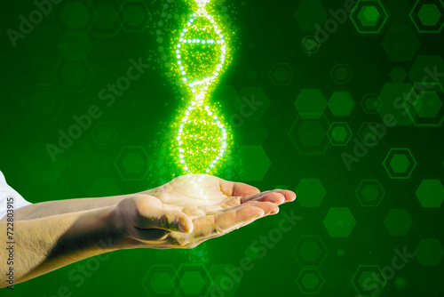 Close up of male hands holding glowing DNA helix on blurry green background. Medical and heredity genetic health concept. Technology science.