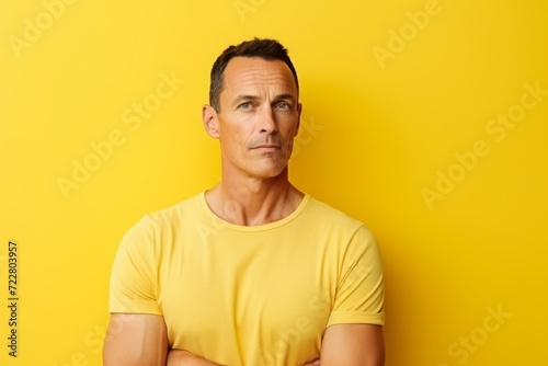 Portrait of mature man in yellow t-shirt over yellow background