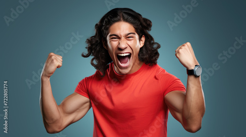 Young man with his fists raised in a victorious gesture, and a broad, joyful smile on his face, likely celebrating a success or win.