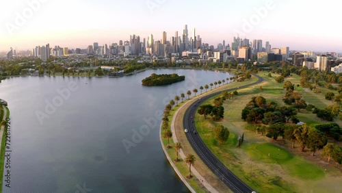Aerial: Australia Melbourne City Center in Background Evening Golden Hour Flight over Beautiful Albert Park Lake