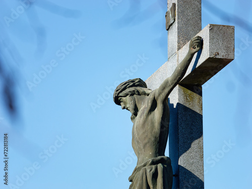 Close-up photo of a beautiful stone sculpture of Jesus on the cross with a clear blue sky in the background placed in the city cemetery of Zapresic, Croatia photo