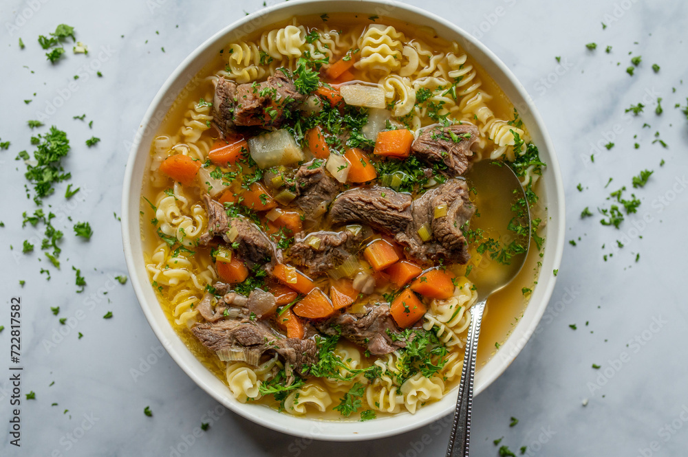 Clear beef soup or stew with noodles and root vegetables isolated on light background. Clear beef soup or stew with noodles and root vegetables isolated on light background.