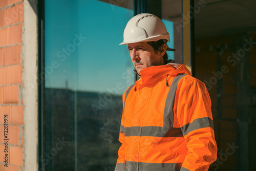 Construction engineer with protective white helmet and high visibility orange jacket on site