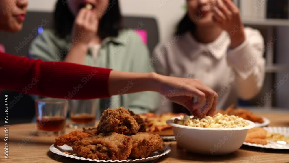 Group of happy young friends celebrating at a party with snacks popcorn pizza and drinks. The atmosphere at the event was full of laughter while sitting at the dining table together in the home office Group of happy young friends celebrating at a party with snacks popcorn pizza and drinks. The atmosphere at the event was full of laughter while sitting at the dining table together in the home office