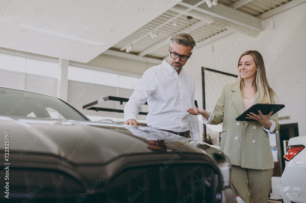 Fototapeta premium Adult man customer male buyer client wear shirt consult with salesman signs documents choose auto wants to buy new automobile in car showroom vehicle salon dealership store motor show. Sales concept.