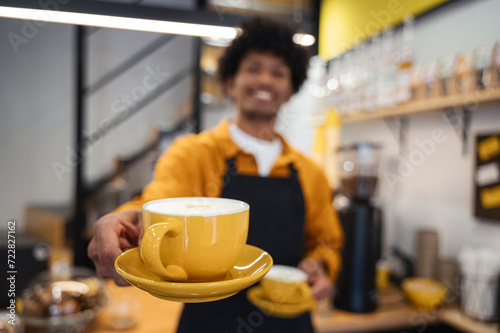 Barista holding yellow coffee cup and saucer photo