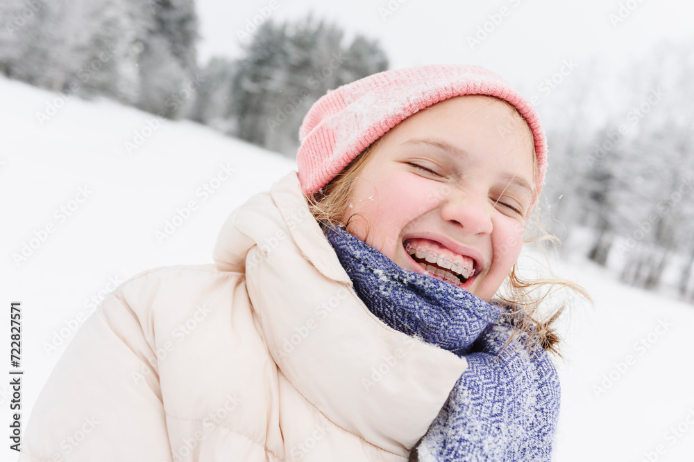Cheerful girl with eyes closed wearing warm clothes on snowfield Cheerful girl with eyes closed wearing warm clothes on snowfield