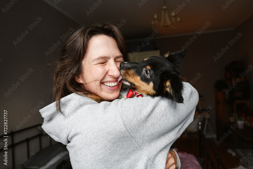 Happy woman with eyes closed holding dog at home Happy woman with eyes closed holding dog at home