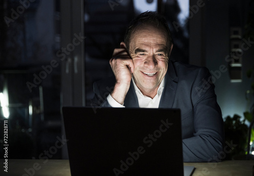 Happy freelancer talking on video conference through laptop at home office photo