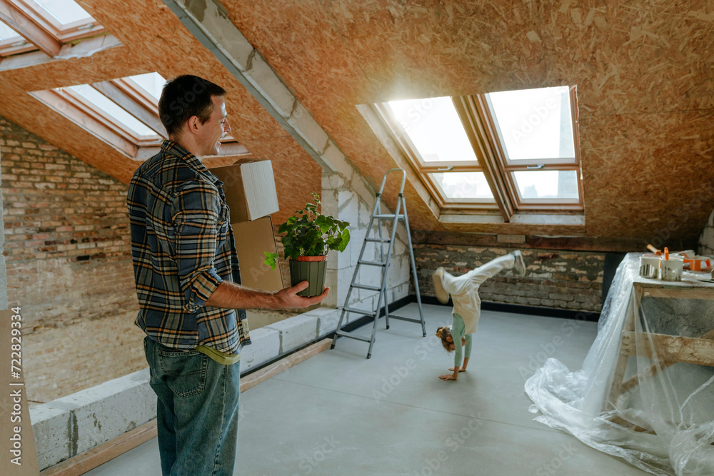 Father looking at daughter doing cartwheel in room under renovation Father looking at daughter doing cartwheel in room under renovation