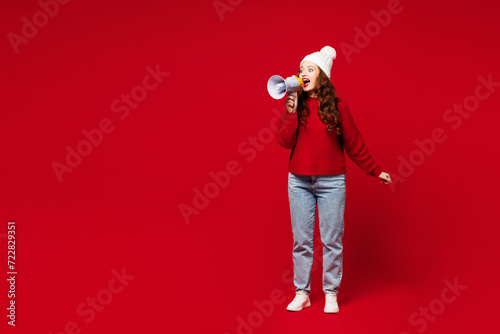 Full body young woman wears knitted sweater white hat casual clothes hold in hand megaphone scream announces discounts sale Hurry up isolated on plain red color background studio. Lifestyle concept.