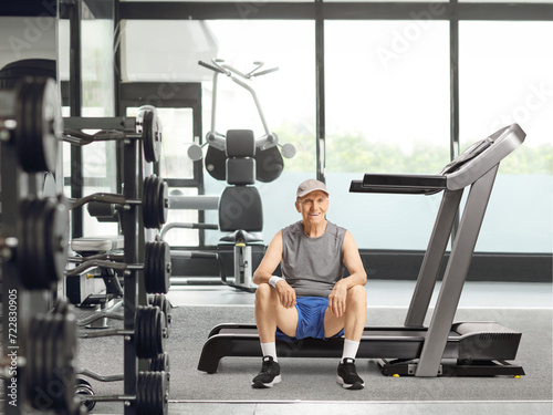 Elderly man sitting on a treadmill at a gym