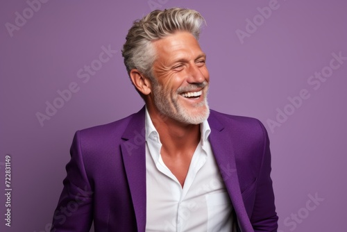 Portrait of a happy senior man laughing while standing against purple background