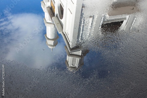 View of the White Mosque with water reflections on the road against a blue sky background photo