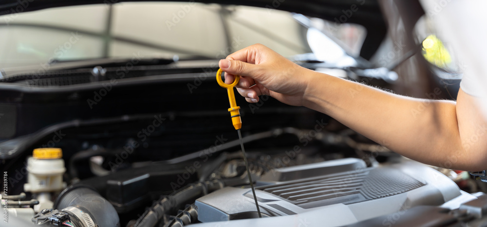 Woman checking car engine oil in the shade working, checking car engine oil.