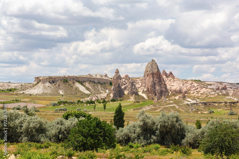 Landscape of a valley in Cappadocia with blue sky and beautiful clouds at background. Cavusin (Nevsehir), Turkey (Turkiye)