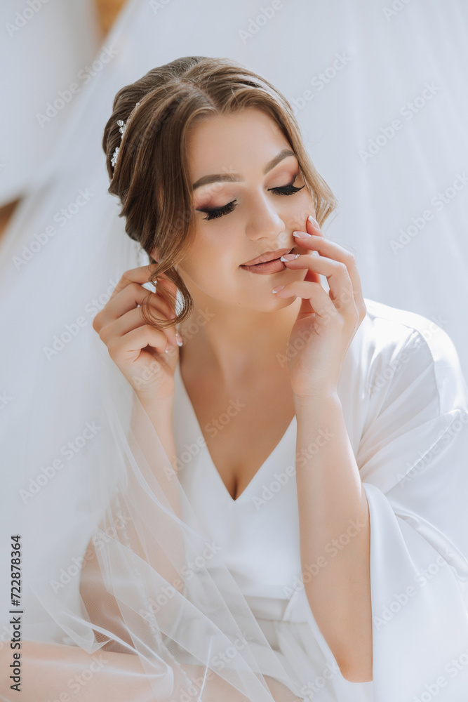 Beautiful, young, perfect model bride in a white lace dress sits in the room, bedroom in the morning, putting an earring on her ear. Wedding photography, portrait, concept. Beautiful, young, perfect model bride in a white lace dress sits in the room, bedroom in the morning, putting an earring on her ear. Wedding photography, portrait, concept.