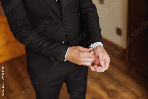 Hands button up the buttons on his shirt. The process of fastening the buttons on his white shirt. Close view. Groom buttons on his shirt cuffs. Morning of the groom