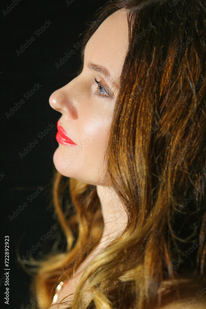 Close portrait in profile with a beautiful brunette girl on a black background. Fashion and beauty concept. Close portrait in profile with a beautiful brunette girl on a black background. Fashion and beauty concept.