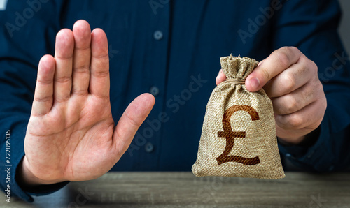 Stop gesture and british pound sterling money bag. Financial difficulties. Asset freeze seizure. Economic sanctions, confiscation of funds. The man does not approve of the transaction or loan. photo