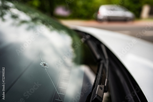 detail of a broken window by a stone in a car on the highway - the cost of replacing the windshield photo