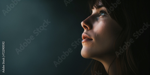 Contemplative young woman in profile, her features accentuated by striking contrast lighting photo