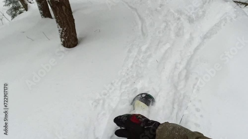 POV a snowboarder rides through a wild forest in a coniferous forest between trees. The camera looks down at the snowboard and the snow in front of the rider. High quality 4k footage