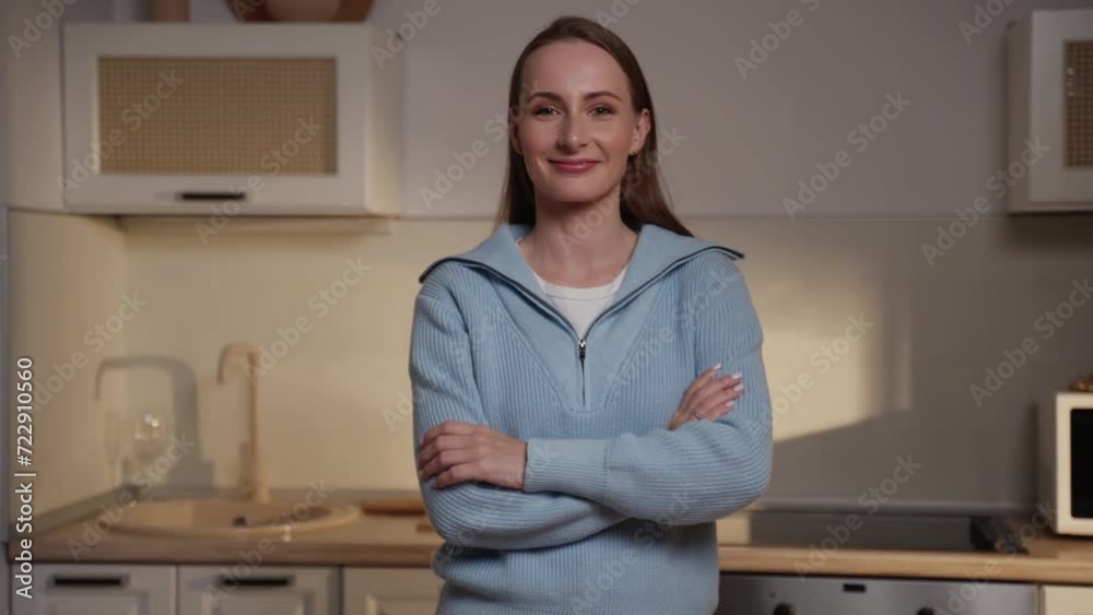 Portrait of a young woman standing at home in the kitchen with her arms crossed over her chest and confidently looking at the camera. Portrait of a young woman standing at home in the kitchen with her arms crossed over her chest and confidently looking at the camera.
