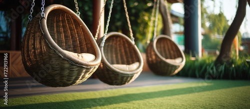 Hanging swings at childrens playground Swings of modern design in the form of a nest with a wicker seat Children s playground has an artificial soft covering. Creative Banner. Copyspace image