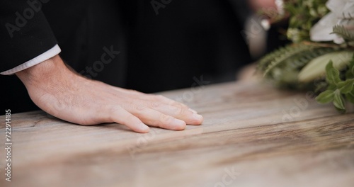 Death, funeral and hand of man on coffin, family at service in graveyard or church for respect. Flowers, loss and people at wood casket in cemetery with memory, grief and sadness at grave for burial.