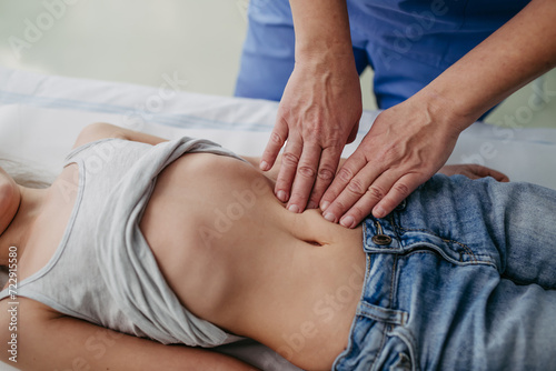 Close up of doctor palpating girl's abdomen, hands and steady pressure on belly. Concept of preventive health care for children.