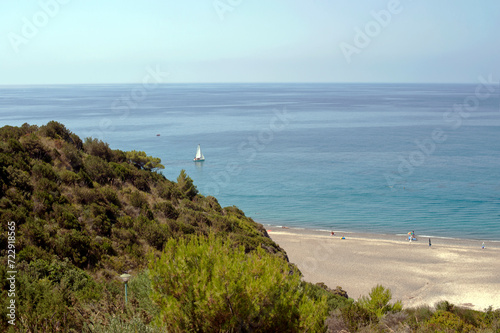 Wild sandy beach next to a cliff with the clear sea disappearing on the horizon. Palinuro. Salerno, Italy. © Tony