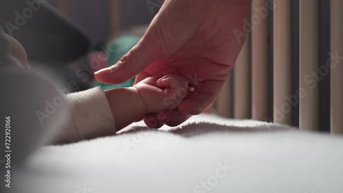 Woman gently touch and hold sleeping newborn baby hand, mother love and care photo