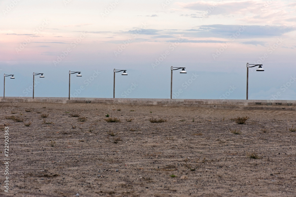 Street lamps in a row beyond the beach.