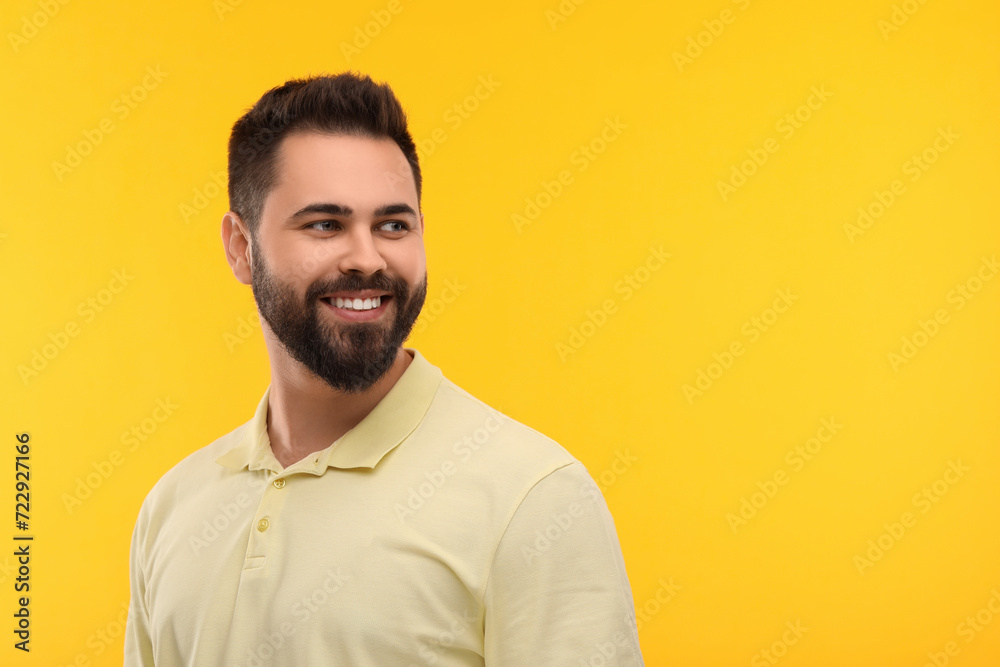 Obraz premium Man with clean teeth smiling on yellow background, space for text