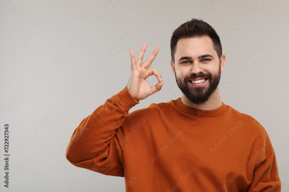Man with clean teeth showing OK gesture on gray background, space for text Man with clean teeth showing OK gesture on gray background, space for text