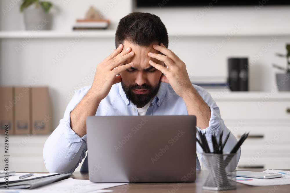 Man suffering from headache at workplace in office Man suffering from headache at workplace in office